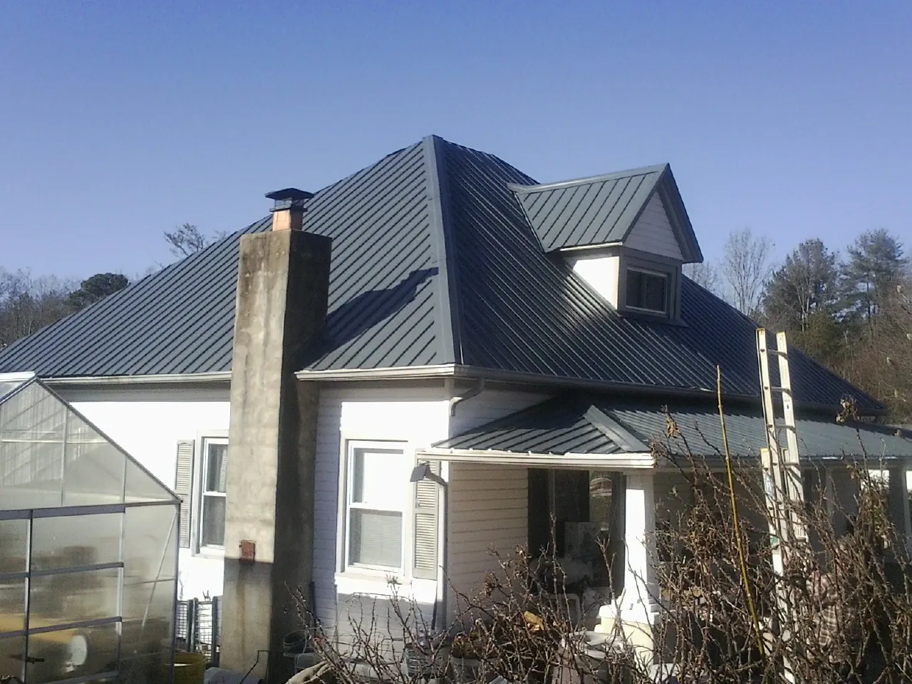 Dark blue standing seam metal roof on a white farmhouse with dormer — Slate & Tile Roof Repair by Roofing Brothers in Readsboro