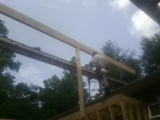 Carpenter setting a ridge beam over a new addition frame — Ice Dam Removal by Roofing Brothers in Readsboro