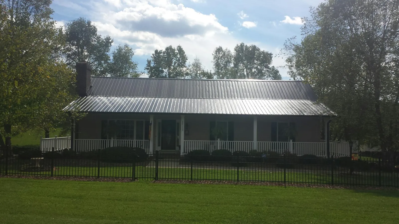 Gray metal roof on a brick ranch with a full width front porch — Gutter Guard Installation work by our crew in Readsboro