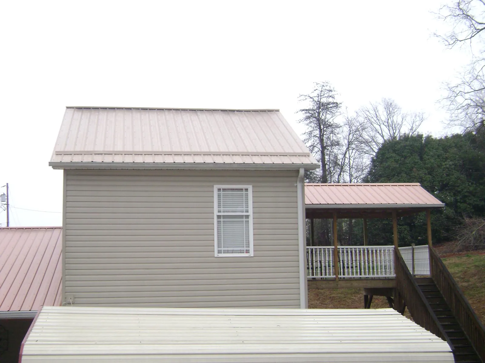 Tan metal roofs on a two story addition and attached porch, from a Roof Replacement job in Readsboro
