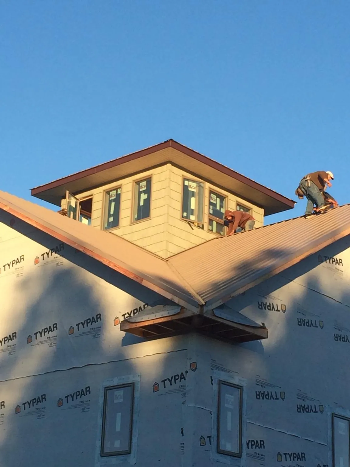 Roofers working around a rooftop cupola on a new metal roof at sunset — Roof Waterproofing in Readsboro by Roofing Brothers